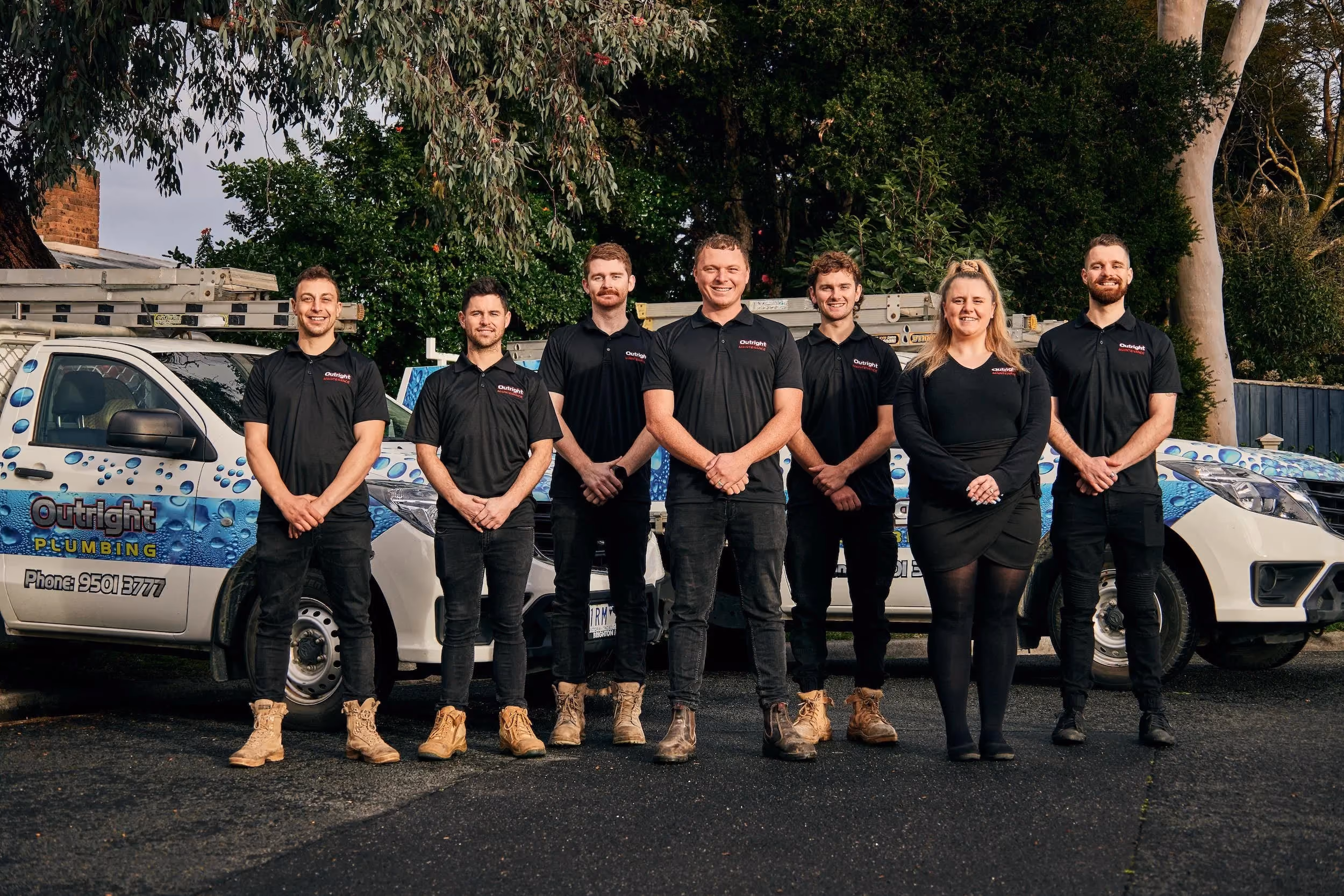 The team Outright Plumbing team standing in front of their vehicles