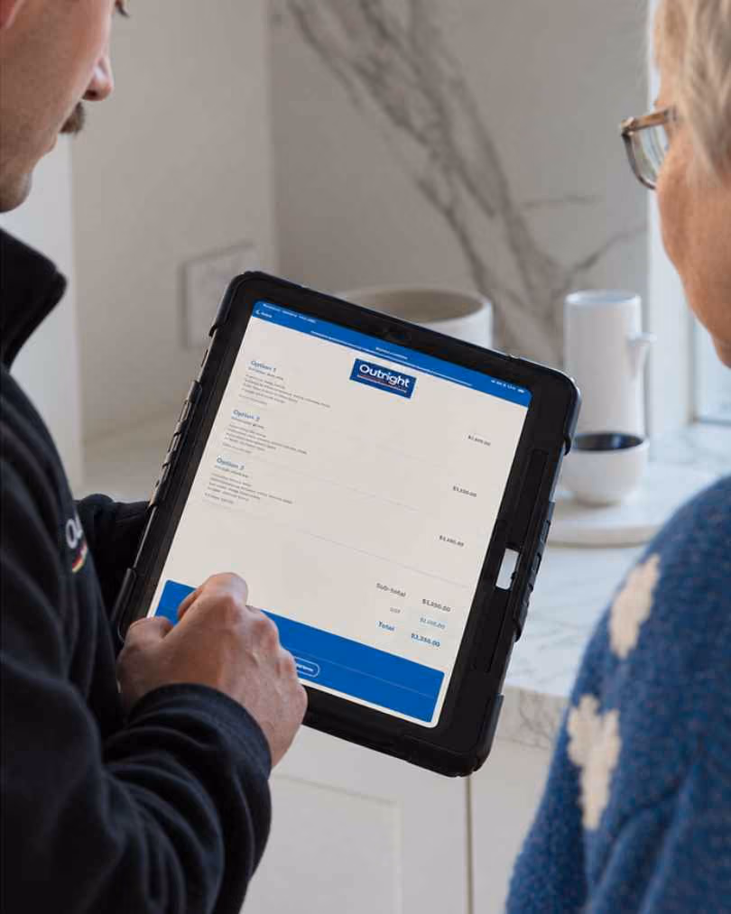 An Outright Plumbing plumber showing a customer three priced options on a tablet.