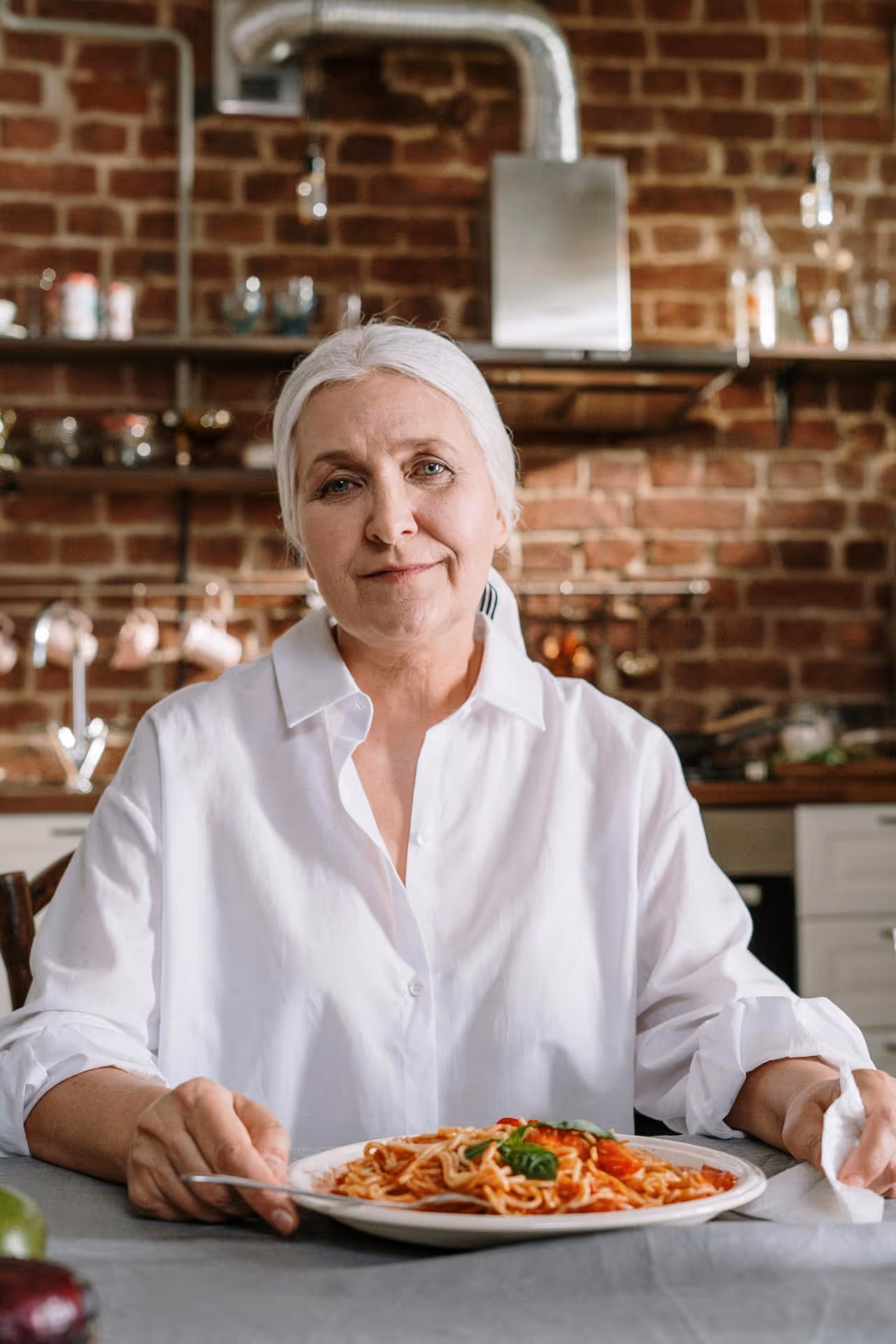Image of an older woman "la nonna" with a plate of pasta.