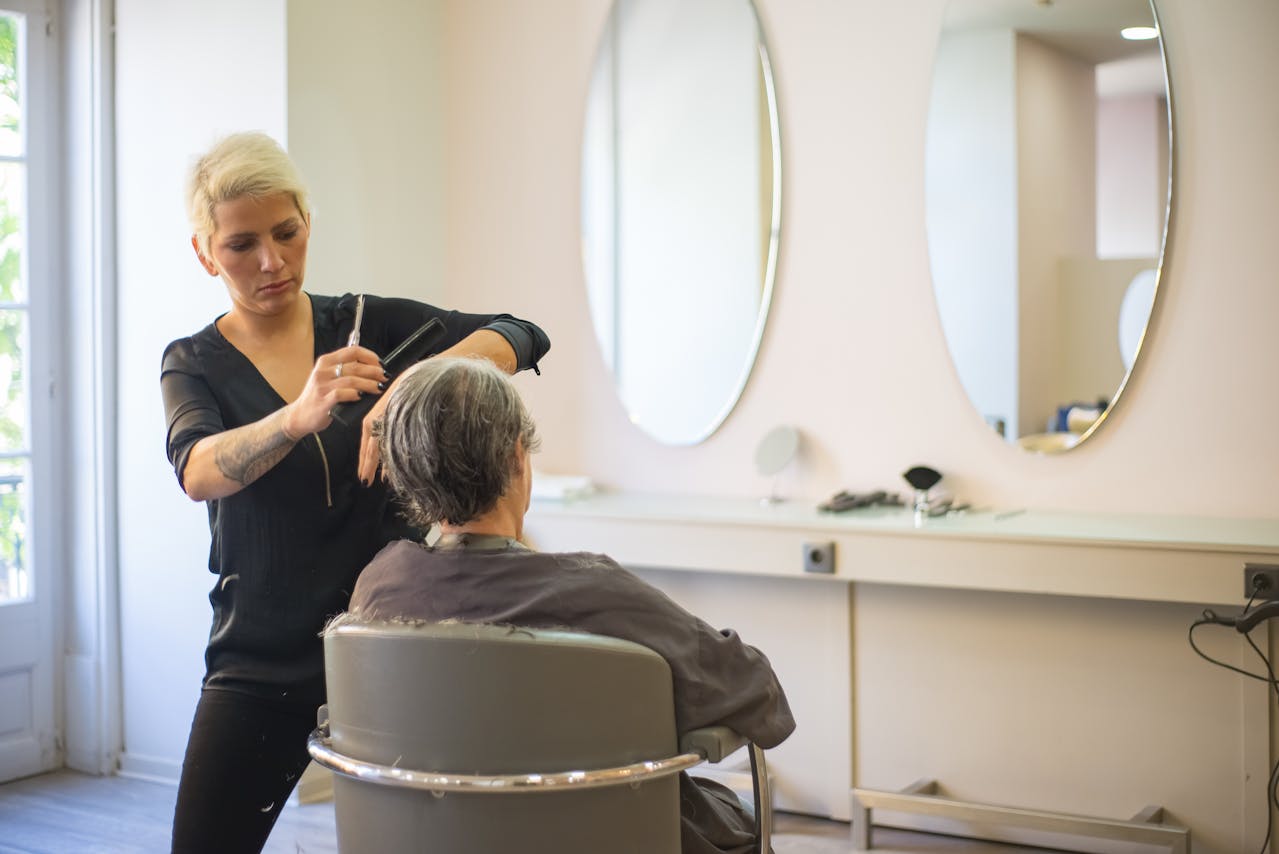 Intérieur moderne de salon de coiffure avec coiffeurs au travail et lumière naturelle