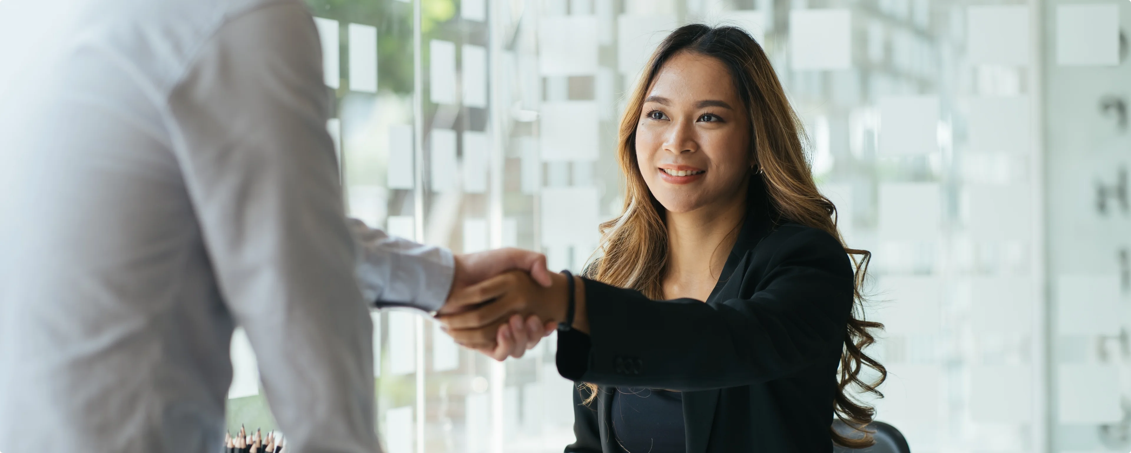 A woman shaking hands with a man in a suit.
