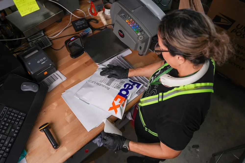 Worker preparing FedEx package for shipping at Palletized fulfillment center
