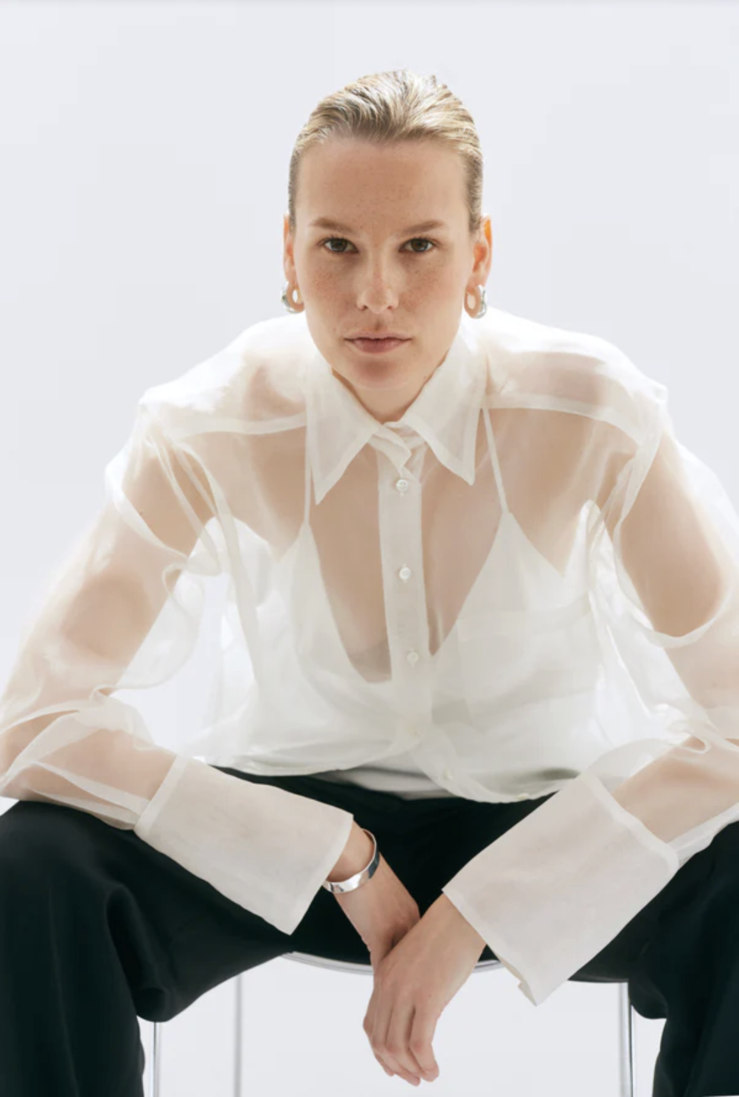 woman wearing white sheer shirt black trousers