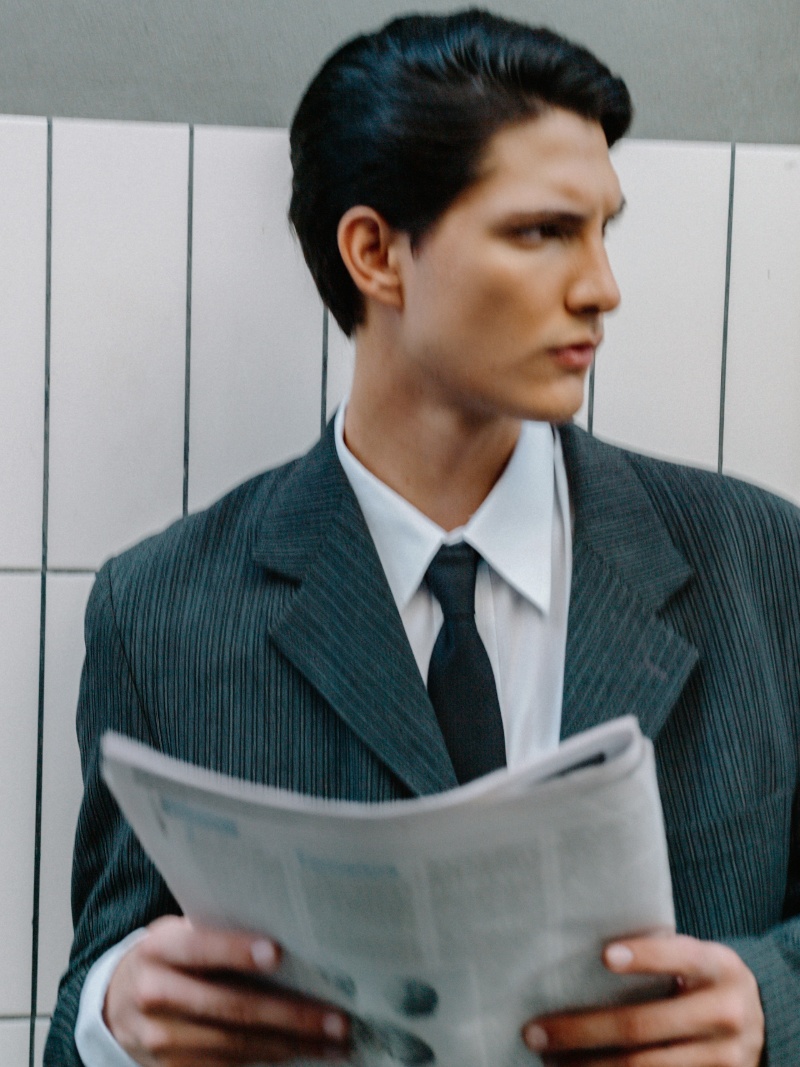 man in suit holding newspaper