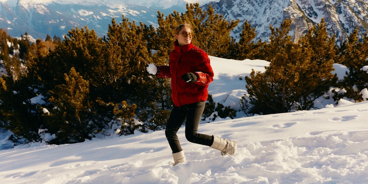 woman in red jacket throwing snowball in snow
