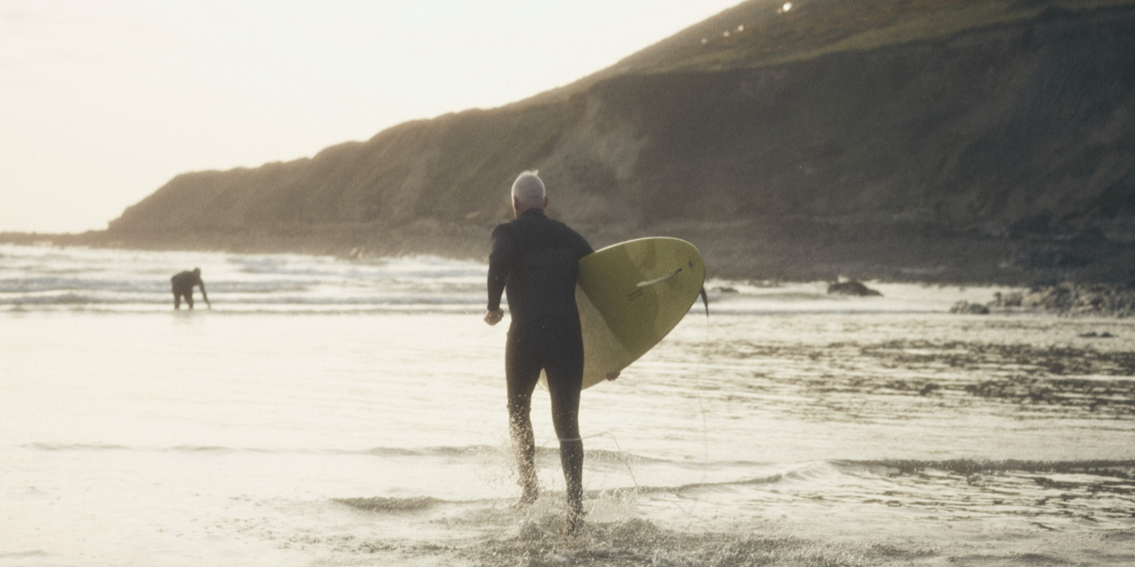 man with surfboard running to ocean