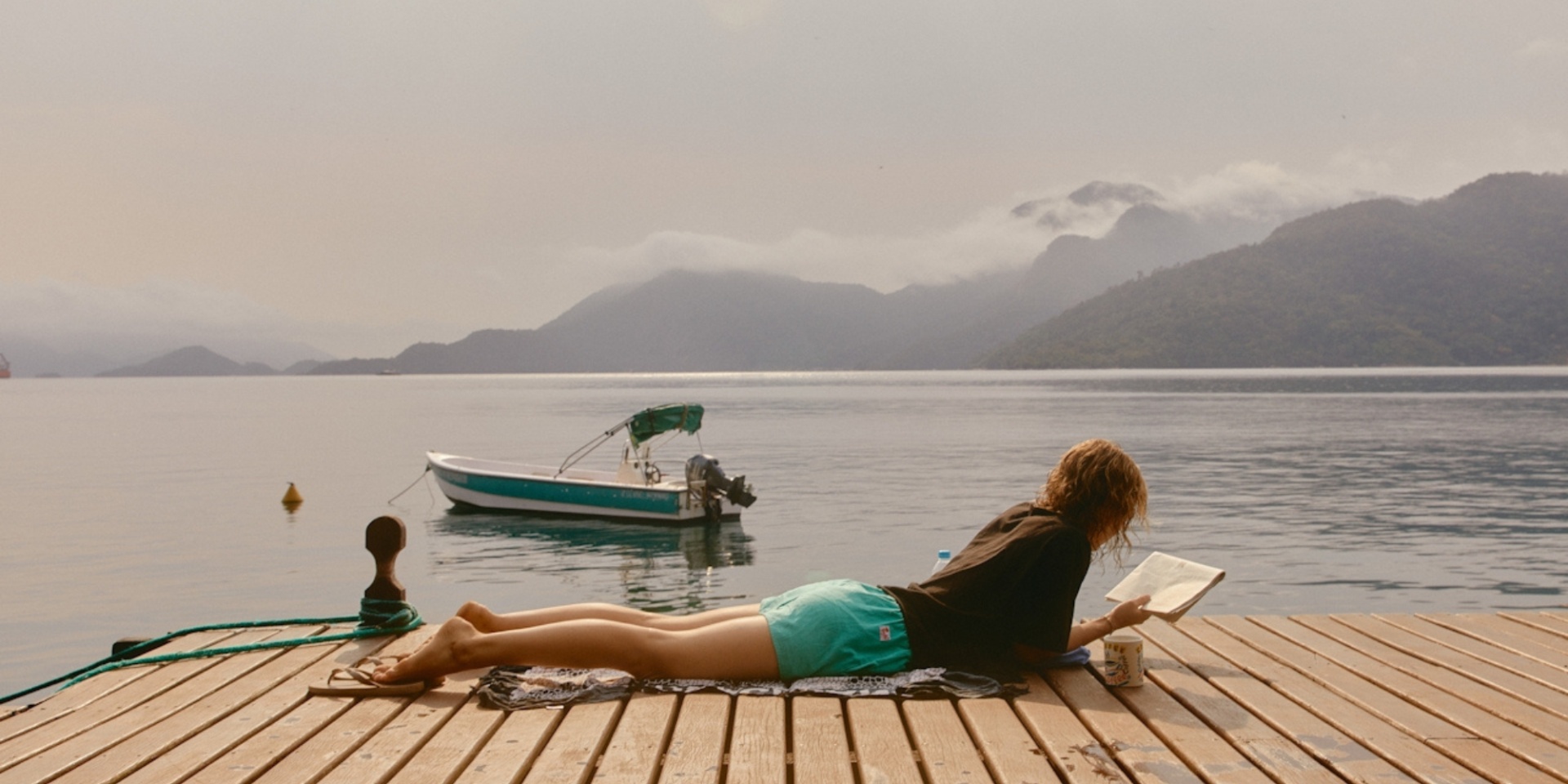 woman lying on wooden dock by sea