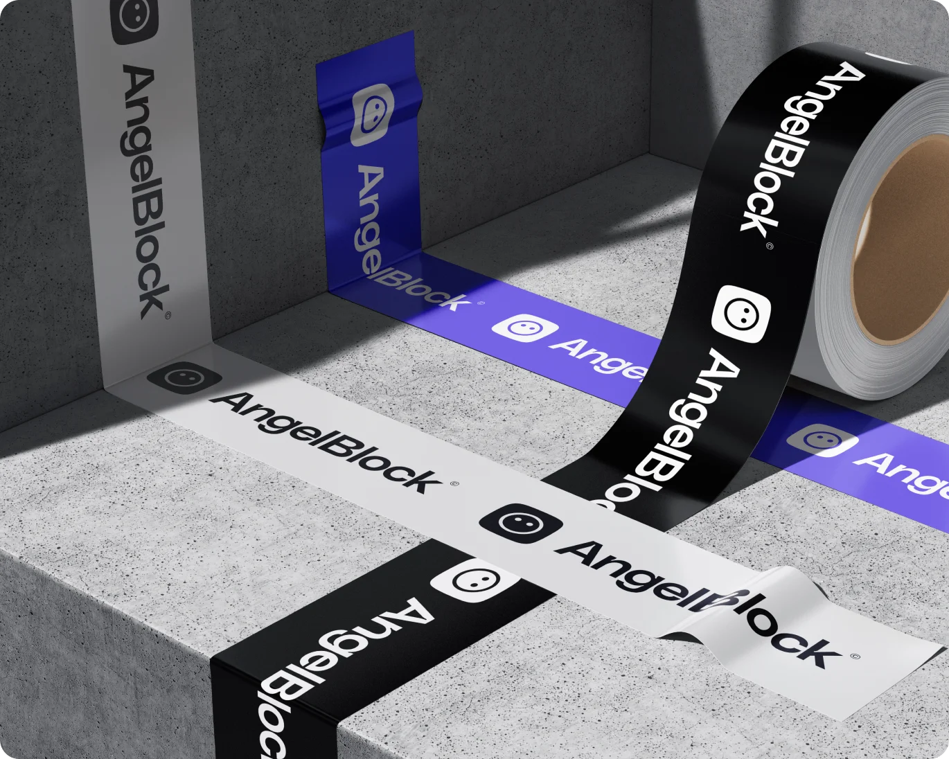 Roll of black AngelBlock branded tape partially unrolled on a concrete surface with white and blue AngelBlock tape strips crossing underneath.