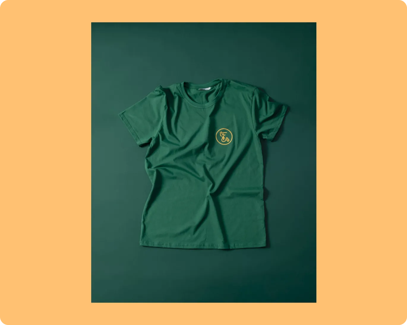 Green short-sleeve t-shirt with a small yellow circular logo on the left chest.