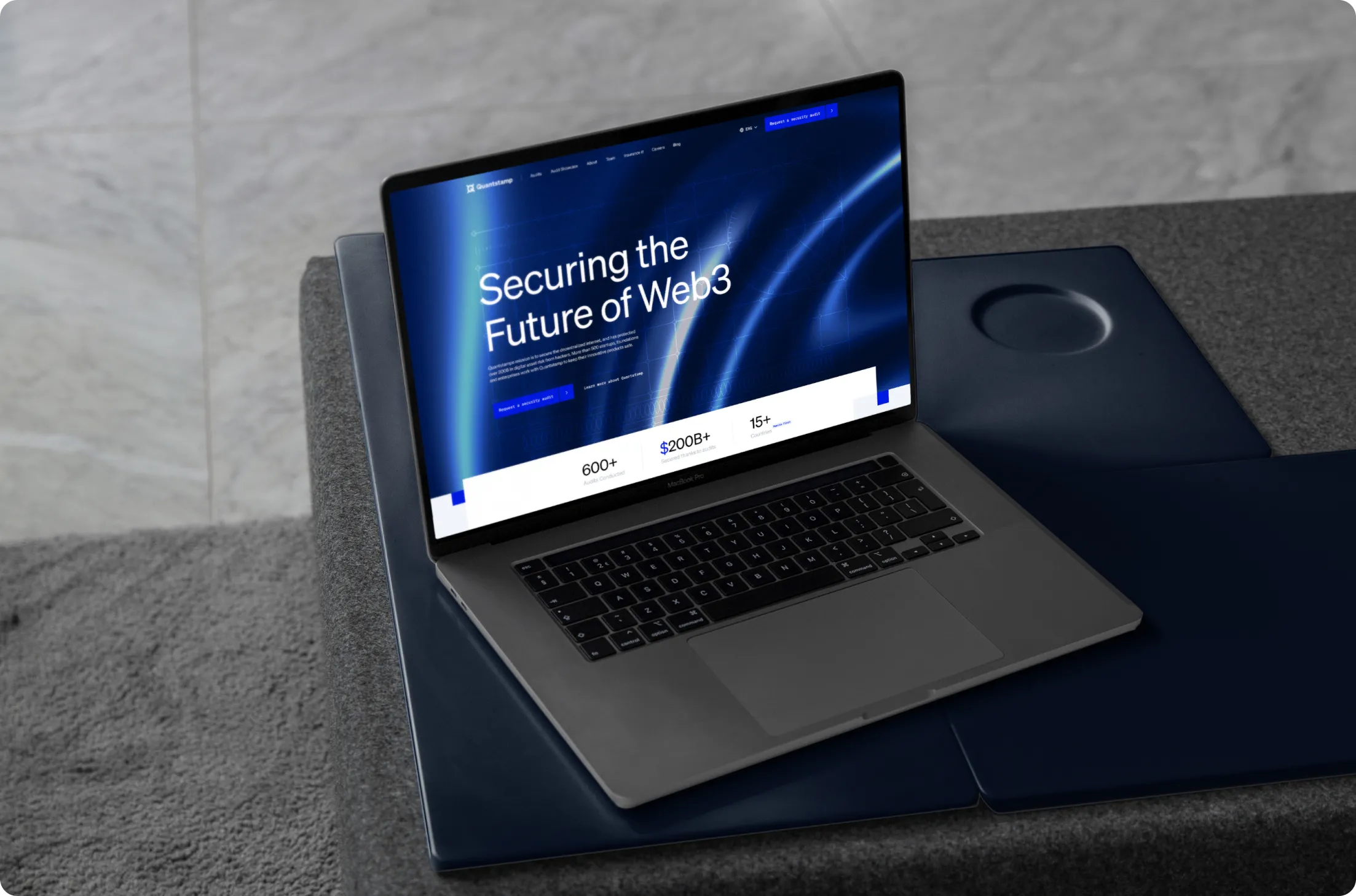 Open laptop on a dark surface displaying a webpage titled 'Securing the Future of Web3' with statistics on assets, funds secured, and audits.