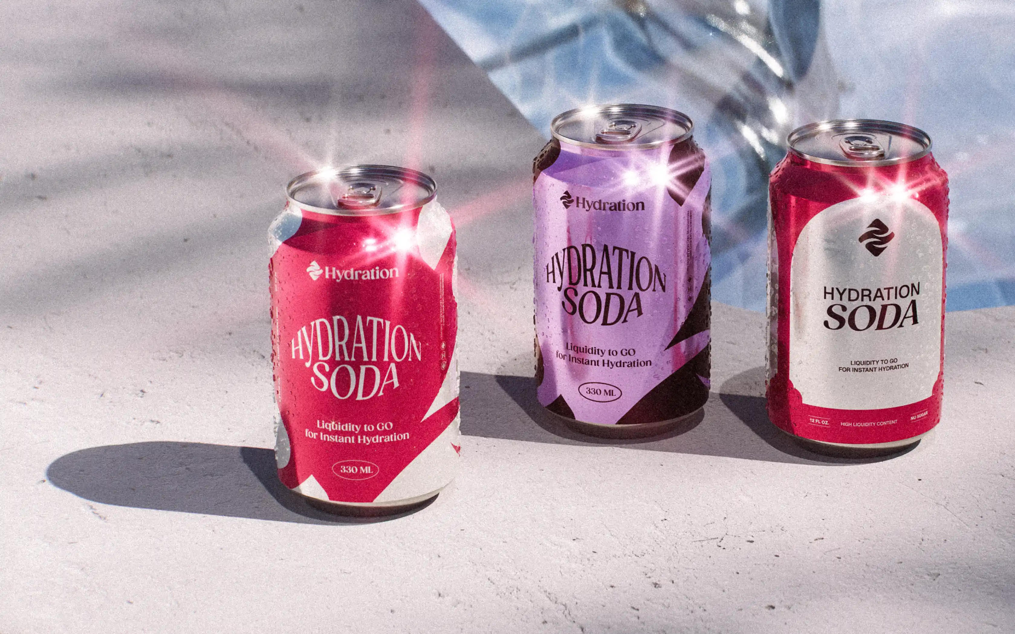 Three cans of Hydration Soda in red and purple colors placed on a light surface with shadows.