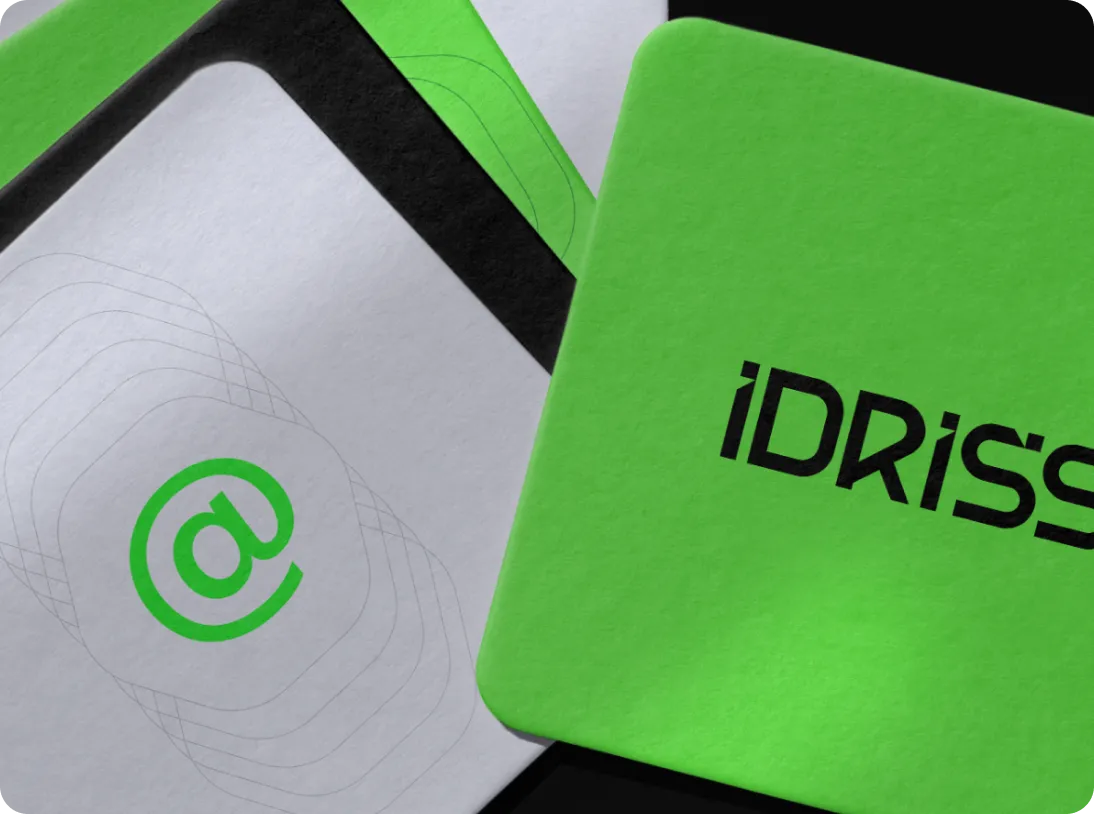 Two overlapping square cards, one green with the black text 'IDRISS' and the other white with a green '@' symbol and black rounded corner design.
