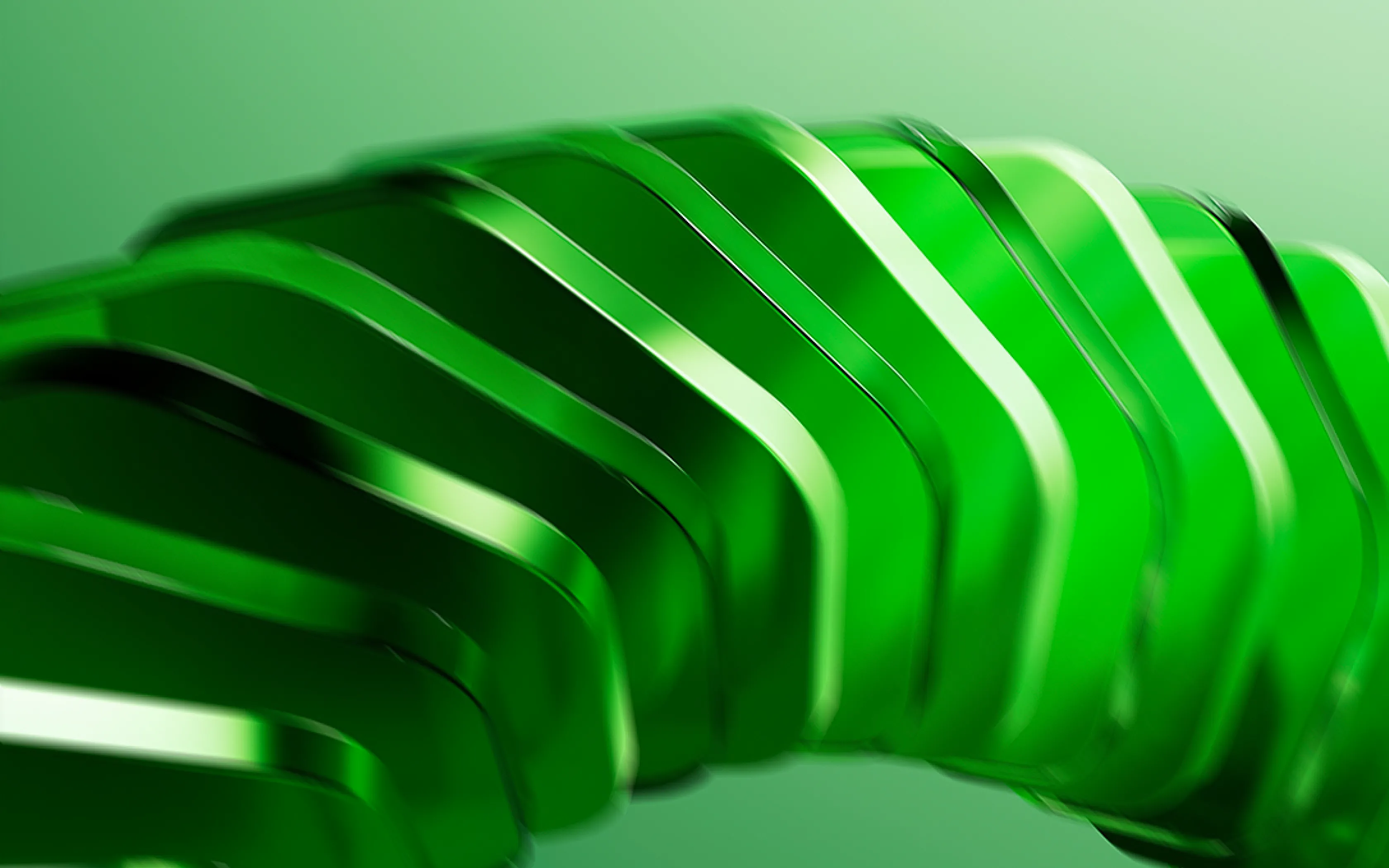 Close-up of shiny, curved green translucent shapes layered together against a green background.