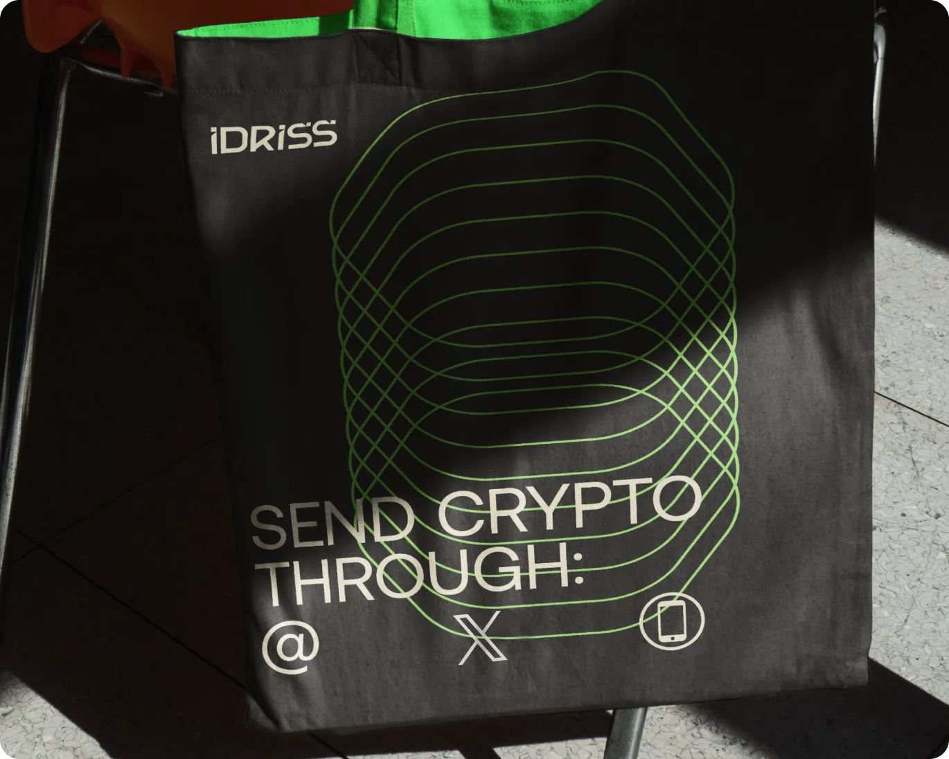 Black tote bag with green abstract lines and text that reads 'SEND CRYPTO THROUGH: @ X' along with a smartphone icon.