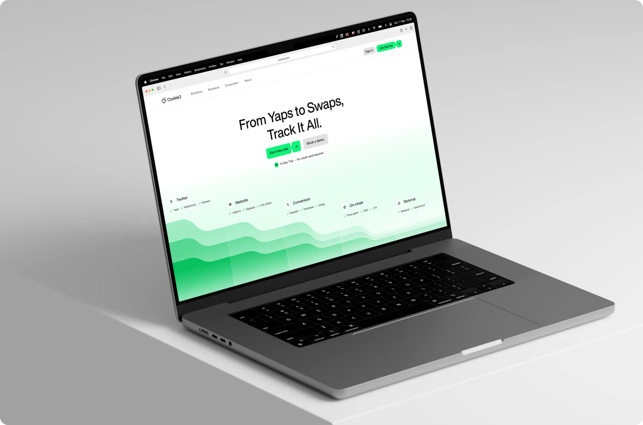 Open laptop on white surface displaying Cookie3 webpage with headline 'From Yaps to Swaps, Track It All' and green call-to-action buttons.