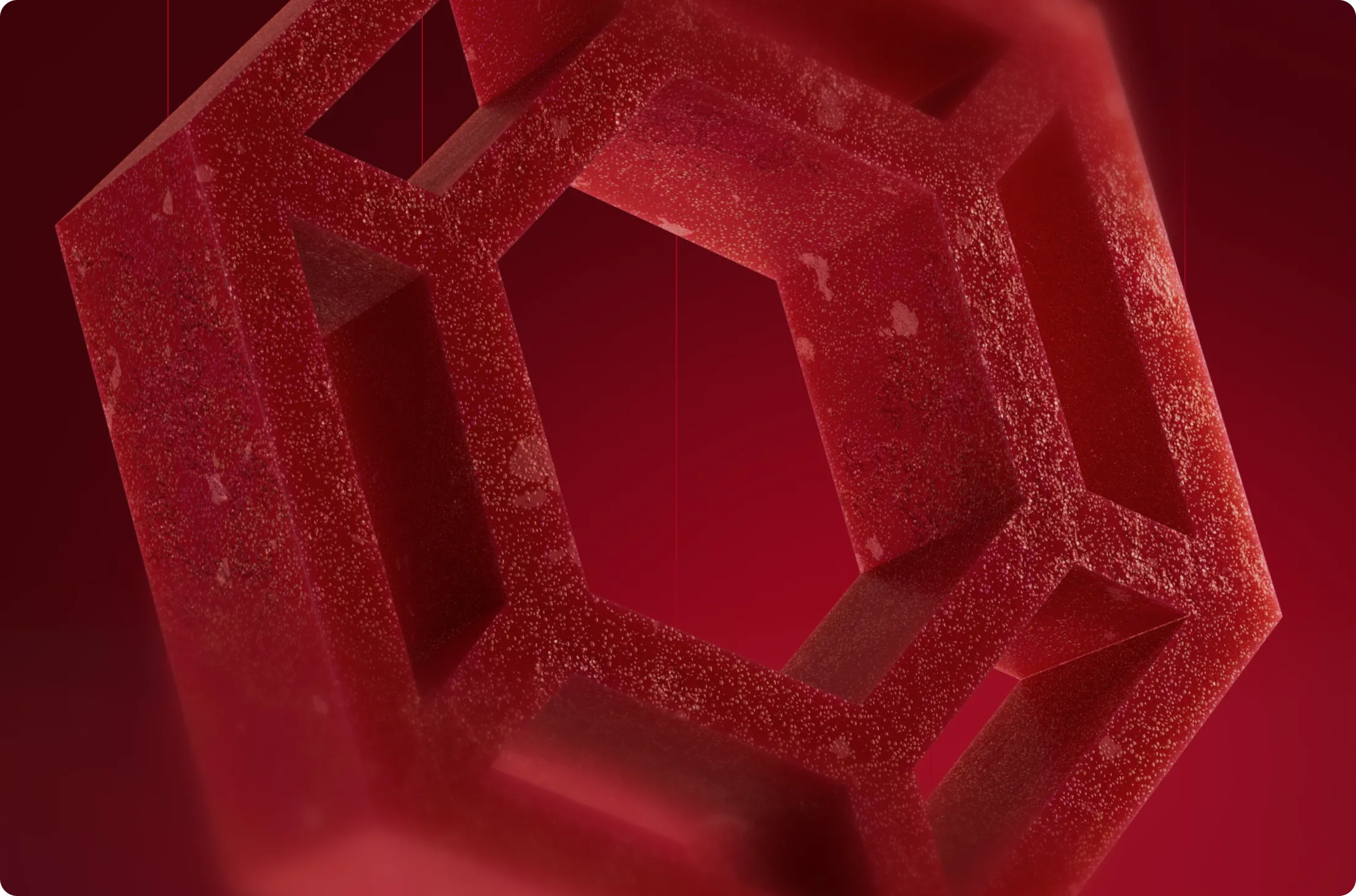 Close-up of a textured, translucent red geometric shape resembling a hollow cube with hexagonal openings against a red background.