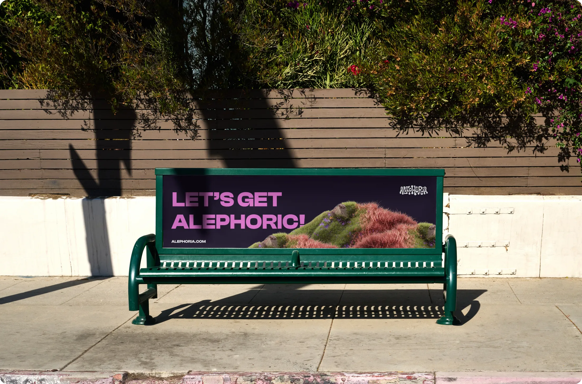 Green metal bench with a dark purple advertisement reading 'LET'S GET ALEPHORIC!' and a grassy hill design in pink and green.