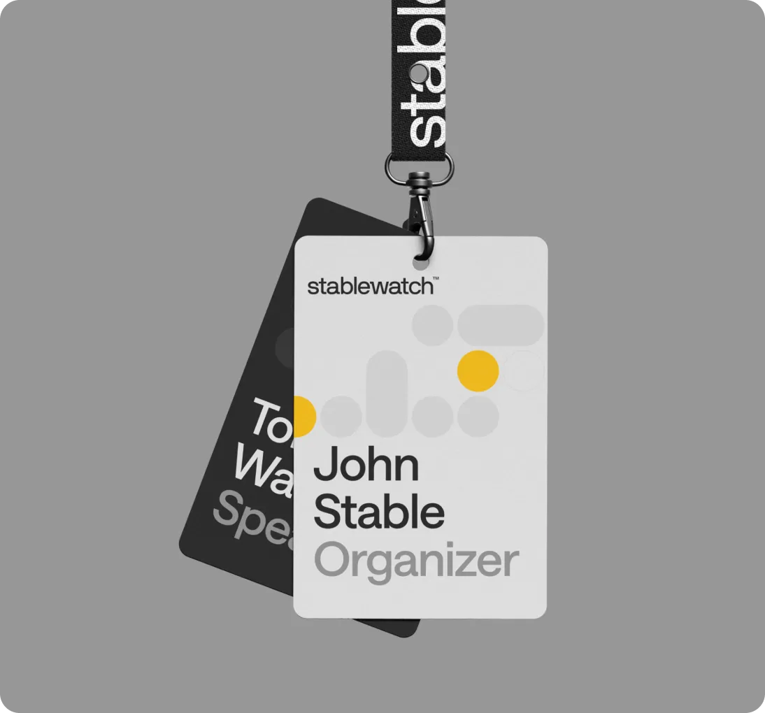Two event badges on a black lanyard with white stablewatch text, front badge shows name John Stable as Organizer with yellow and gray circular design.