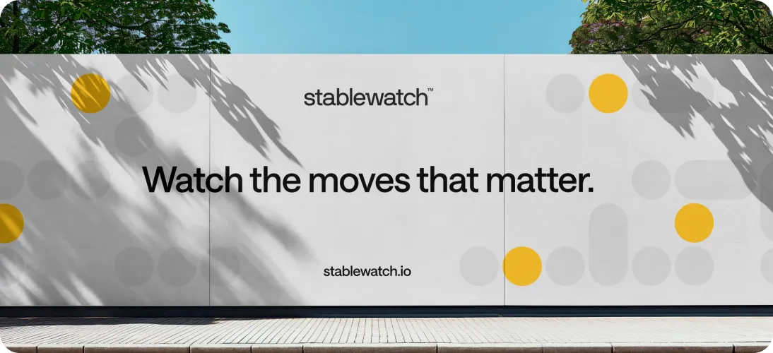 Outdoor advertisement on a white wall with text 'stablewatch™ Watch the moves that matter.' and 'stablewatch.io' surrounded by yellow and gray circular graphics.