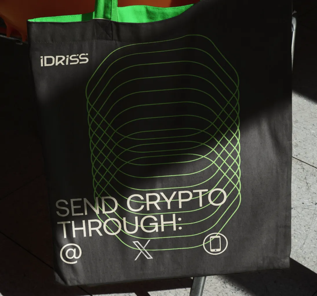 Black tote bag with green interior featuring the text 'SEND CRYPTO THROUGH:' and icons of an at symbol, an X, and a smartphone.