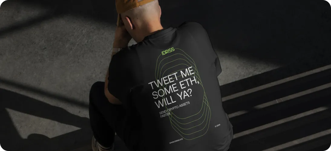 Person wearing a black shirt with text 'TWEET ME SOME ETH, WILL YA? SEND CRYPTO ASSETS FASTER' and geometric design on the back.