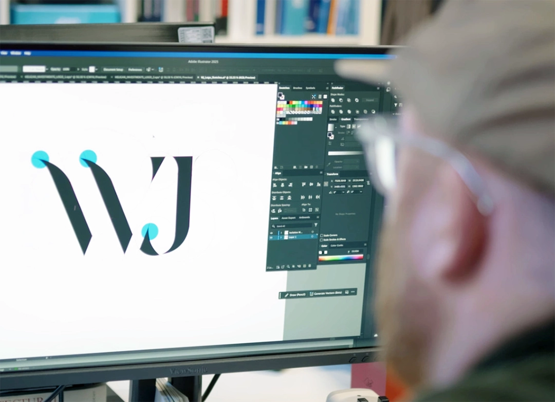Person working on a computer editing a logo with letters 'WJ' in Adobe Illustrator.