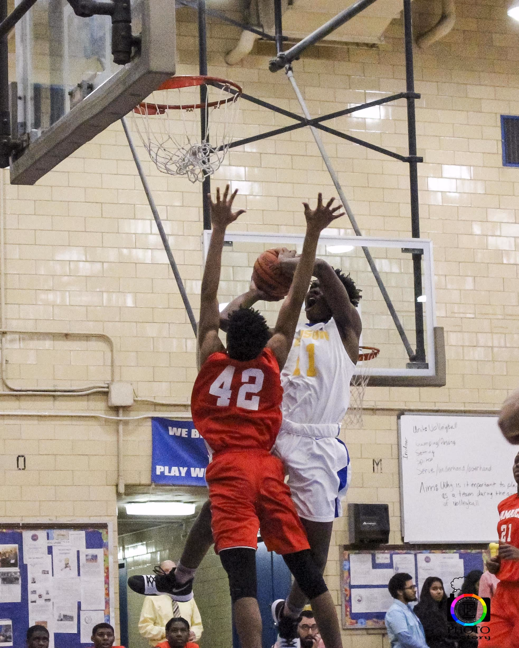 Two students competing in a school basketball game near the hoop
