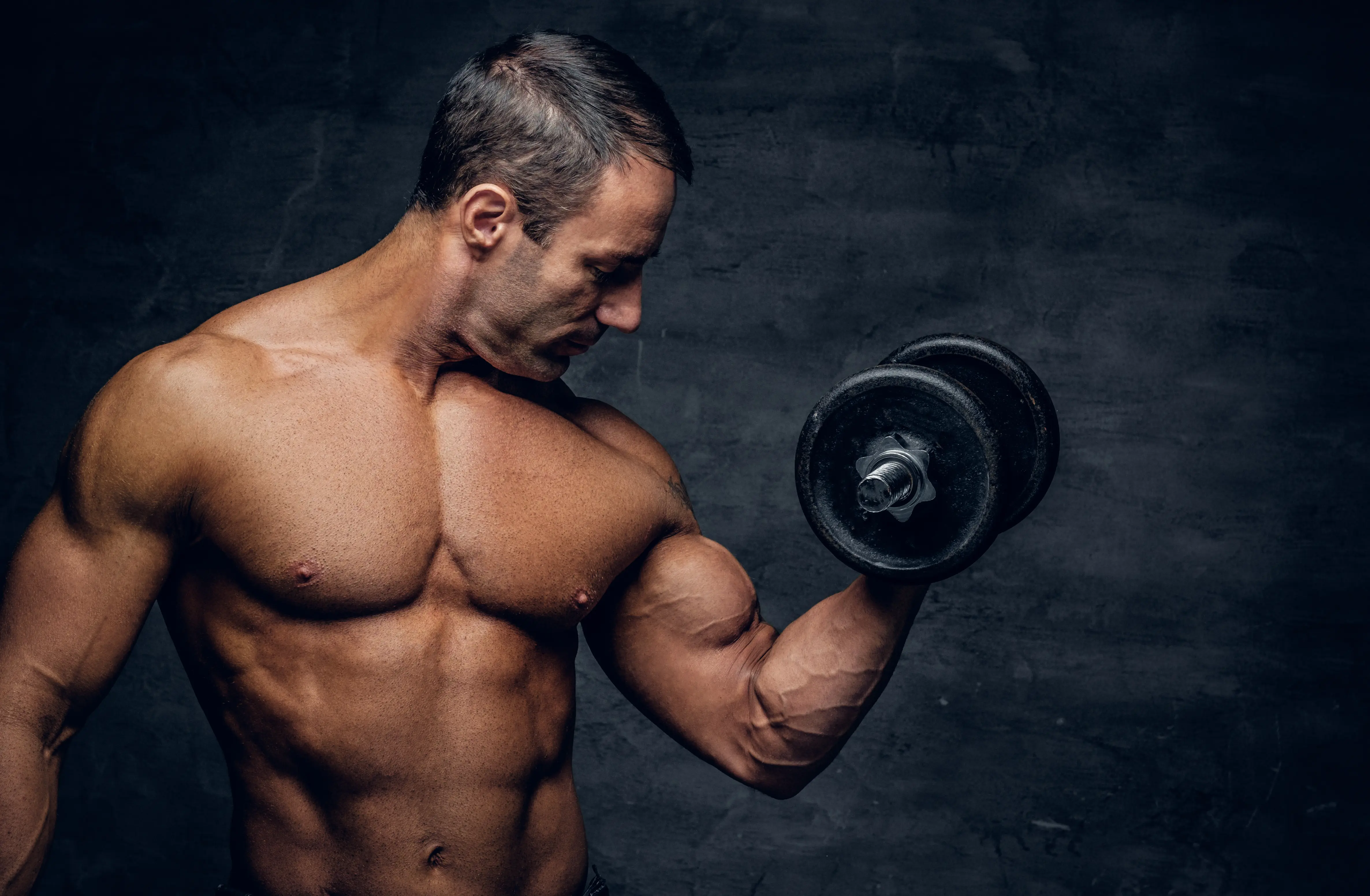 A shirtless man is holding a dumbbell.