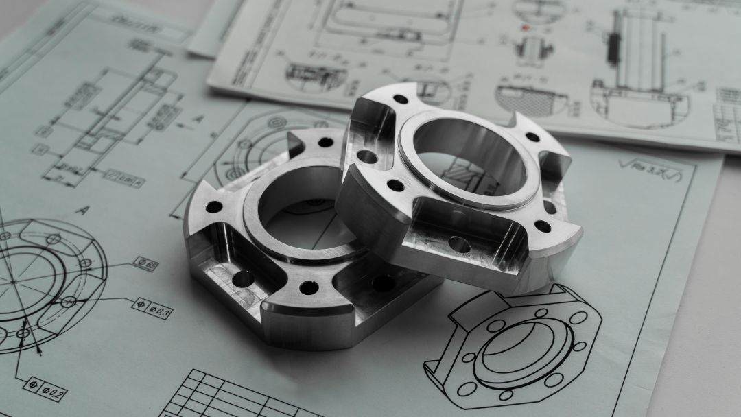 Machined metal components placed on technical drawings.
