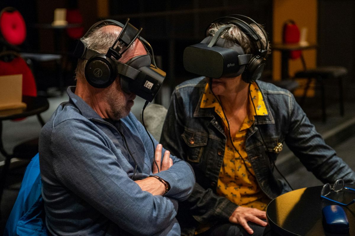 Two people wearing VR headsets sitting and interacting.