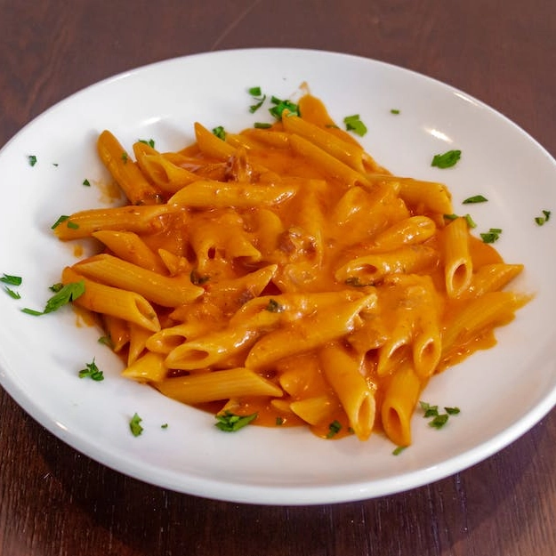 A white plate with a bowl of pasta on it.