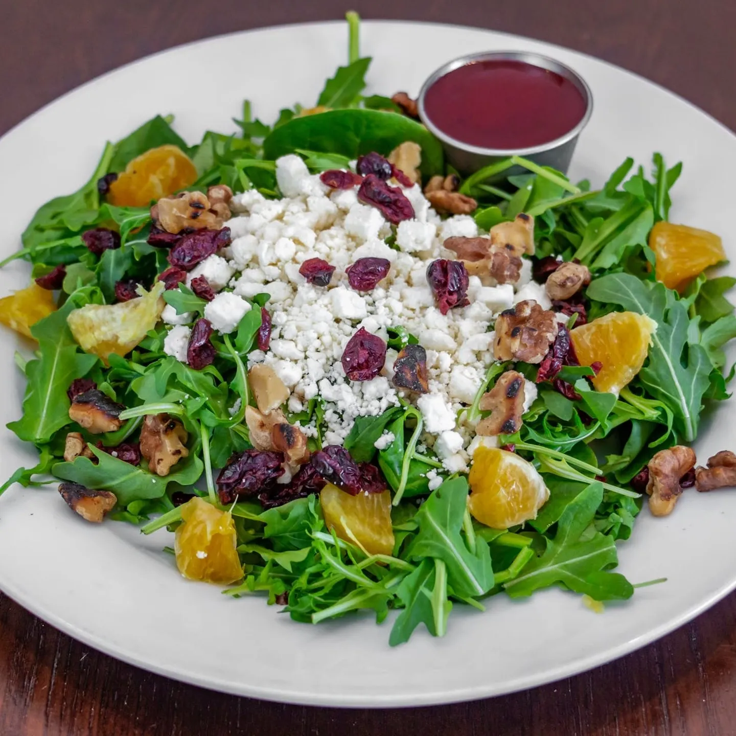 A plate of salad with orange slices and feta cheese.