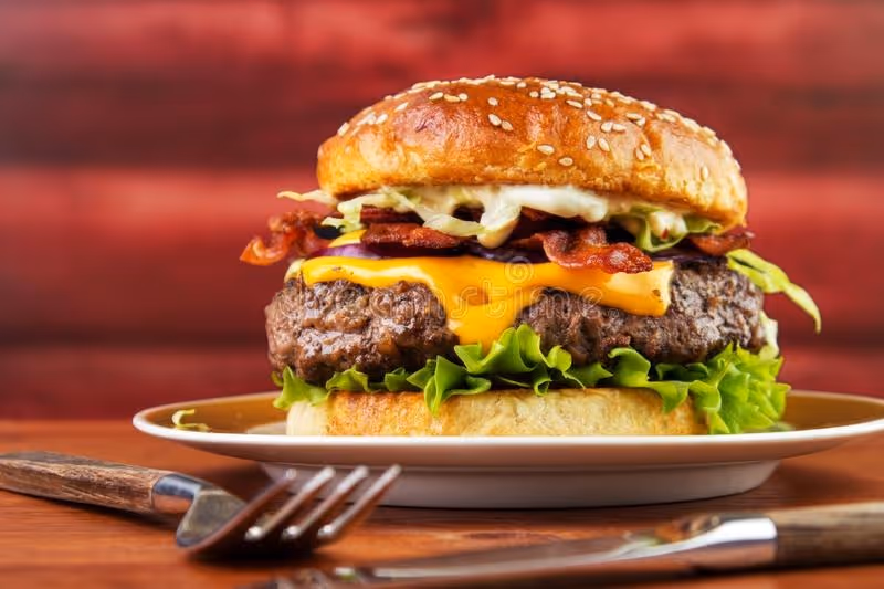 Grilled cheeseburger with crispy bacon on a golden sesame seed bun topped with fresh lettuce.