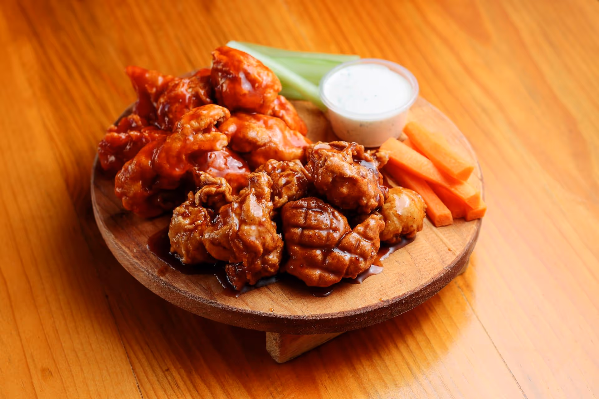 Deliciously seasoned chicken wings served with crunchy carrots, celery sticks, and tasty dip nearby.