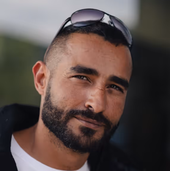 Customer testimonial photo of a man with a trimmed beard and sunglasses resting on his head