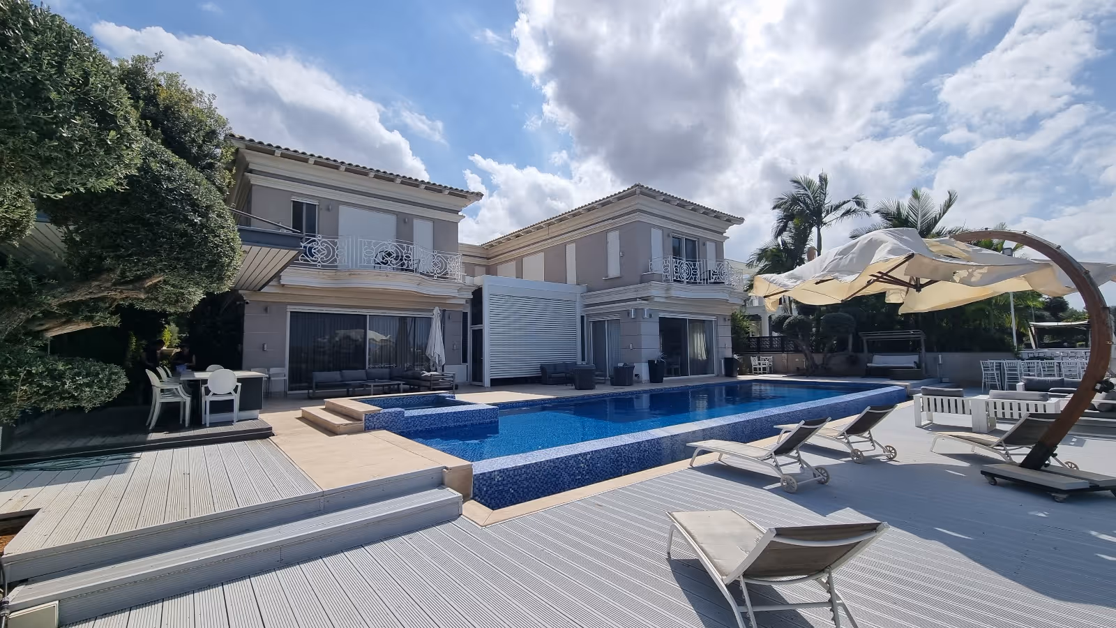 וילה מודרנית עם בריכה גדולה, שמיים כחולים וצמחייה טרופית – רקע לאתר שמאות מקרקעין