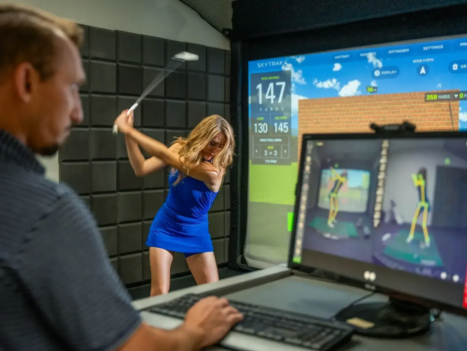 Golf instructor using OPTIMOTION to record student swing during a golf lesson in a golf simulator bay.