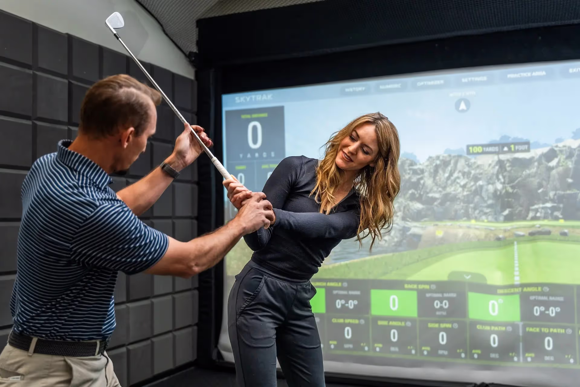 Coach working with woman on proper stance during a golf swing