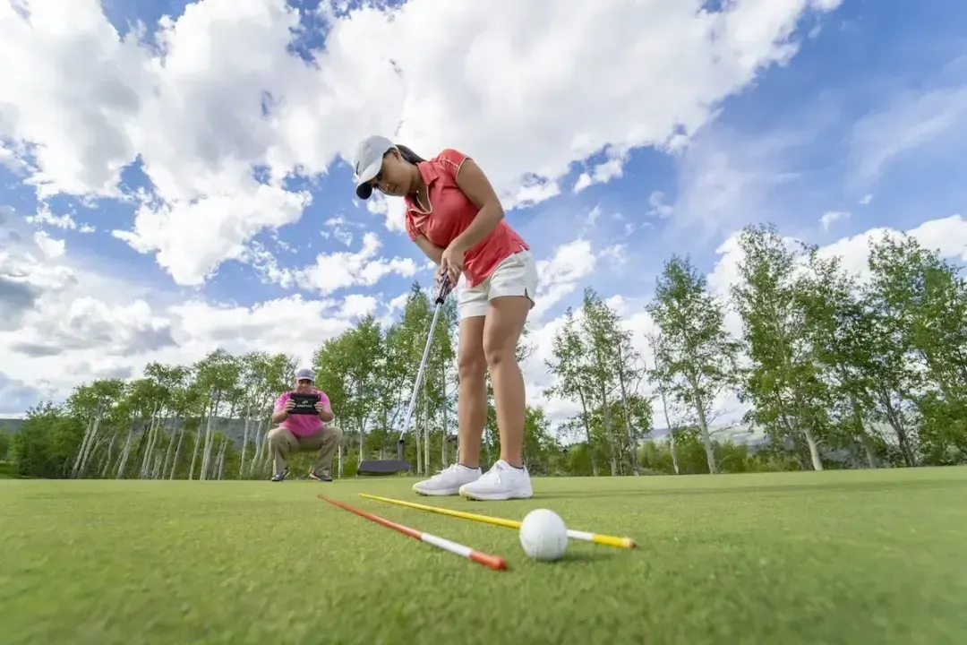 Practicing putts on green with alignment rods and video recorded by GOLFTEC coach
