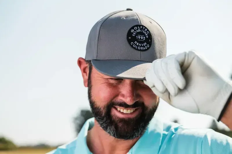 Man smiling wearing a GOLFTEC hat