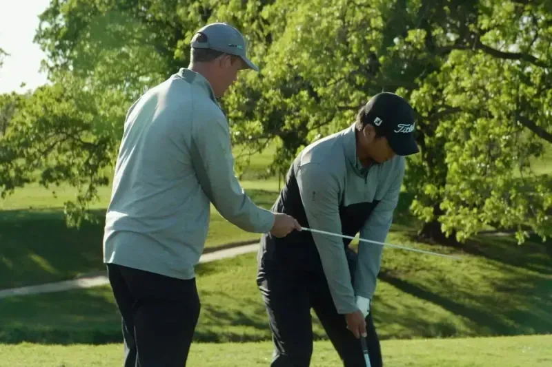 Outdoor golf practice with GOLFTEC coach using alignment rod with student