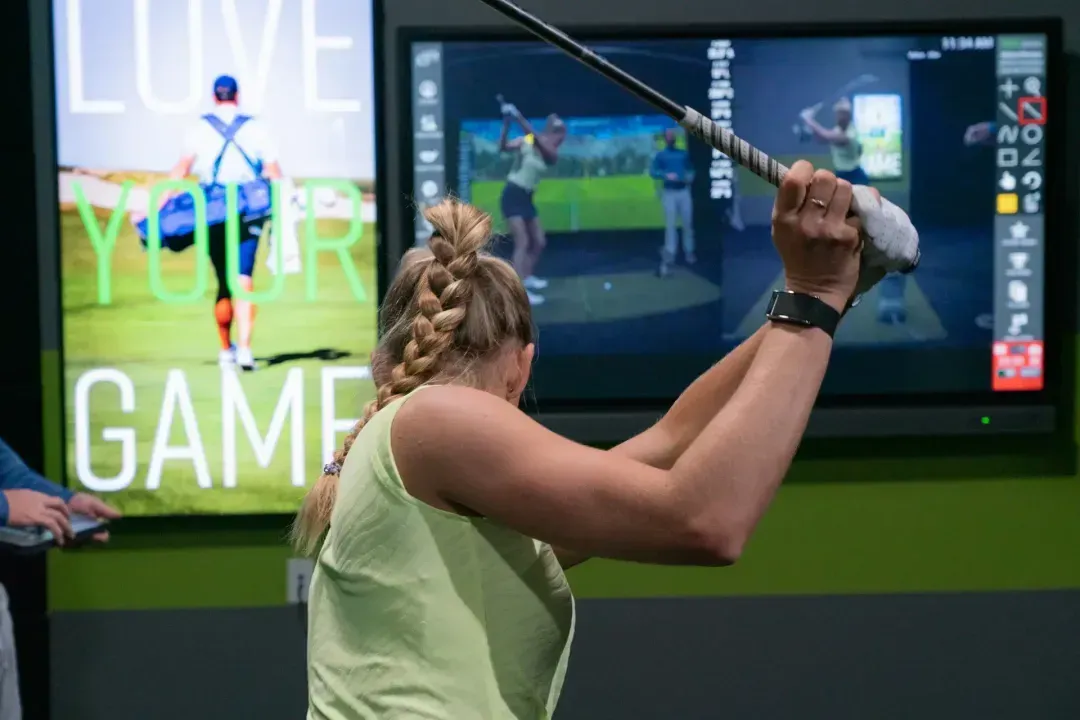 Close up view of woman practicing her swing in a GOLFTEC center