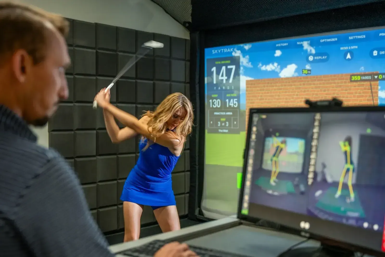 Golf instructor using OPTIMOTION to record student swing during a golf lesson in a golf simulator bay.