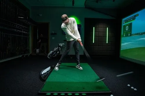 Side view of a man practicing at a GOLFTEC center bay, using a simulator studio and advanced technology to improve skills 