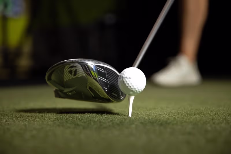 TaylorMade Qi35 Driver teed up on the tee box with a golfer in stance,  ready to hit.