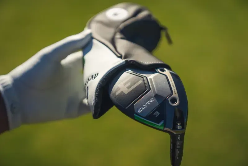 Golfer removing the headcover from a Callaway club on the course. 