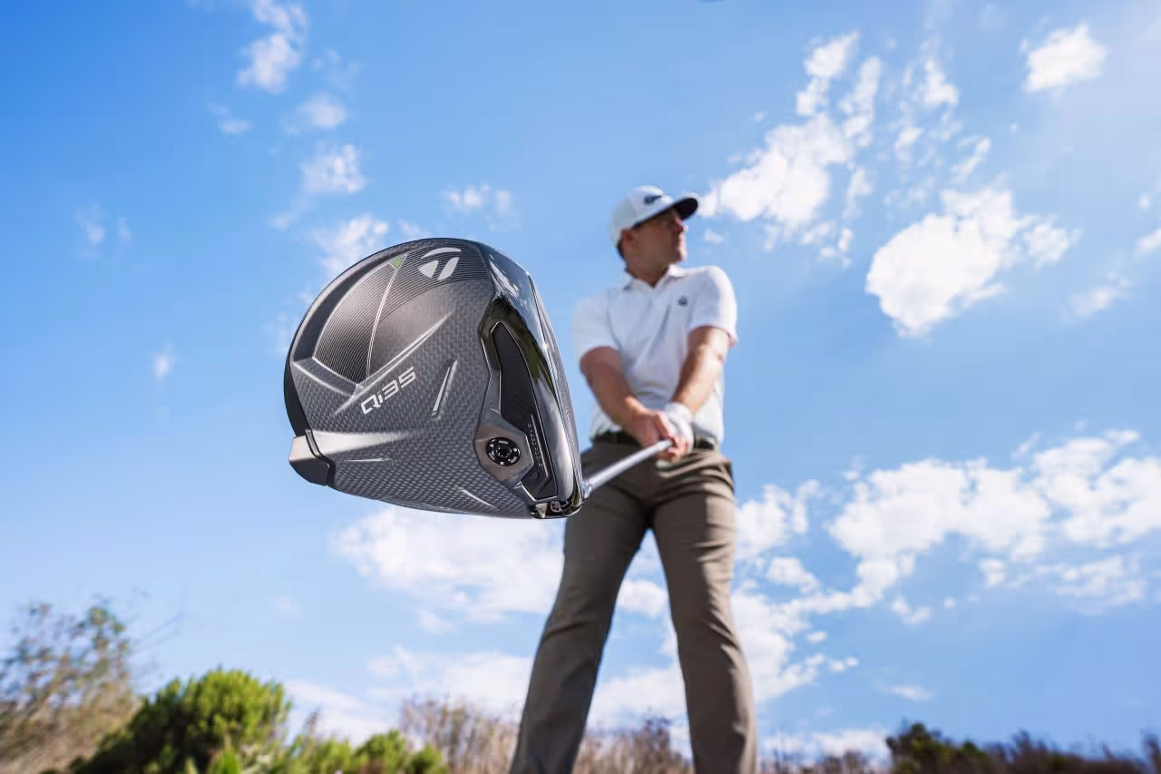 Bottom view of a TaylorMade driver head, with golfer holding the club and sky above 