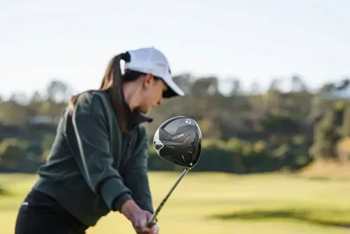 Woman in mid-backswing with a TaylorMade Q35i MAX Lite driver on the golf course