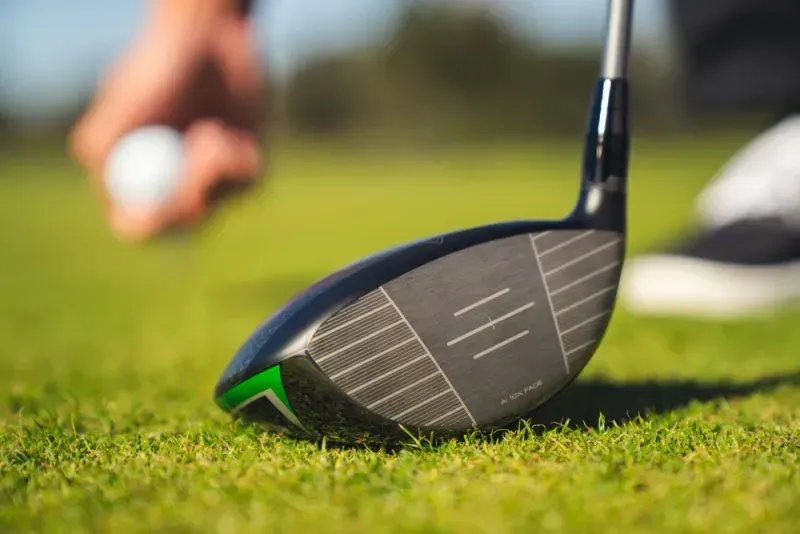 Zoomed-in view of the clubface of the Callaway Elyte driver with a golfer placing the ball in the tee box. 