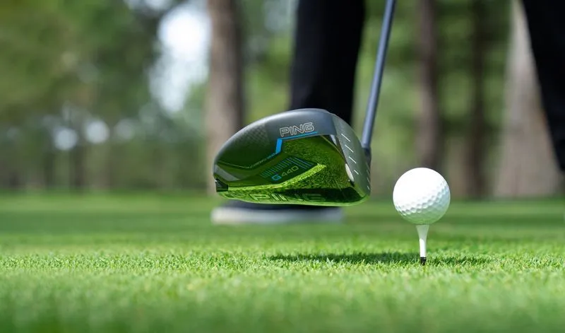 Golfer prepares to swing with PING G440 driver, addressing teed-up ball in the tee box